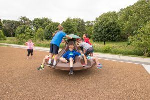 Group of children on brown playground spinner