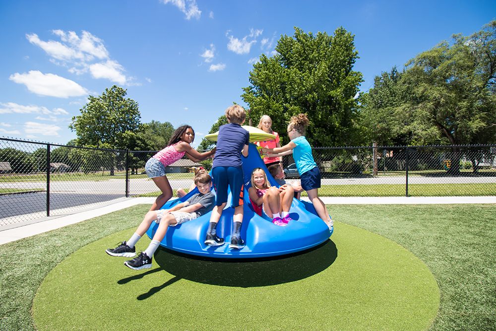 Group of children on blue spinning playground equipment for the First Baptist Church