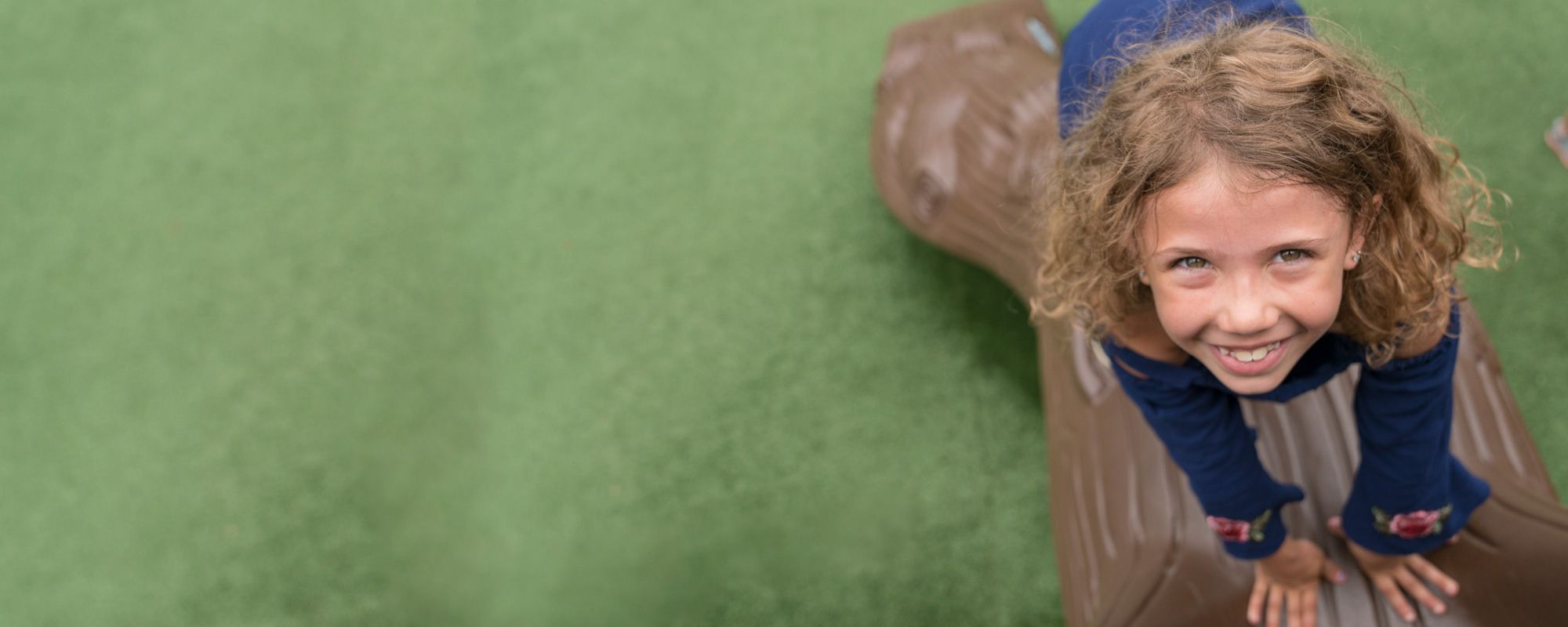 Child Smiling on Green Floor