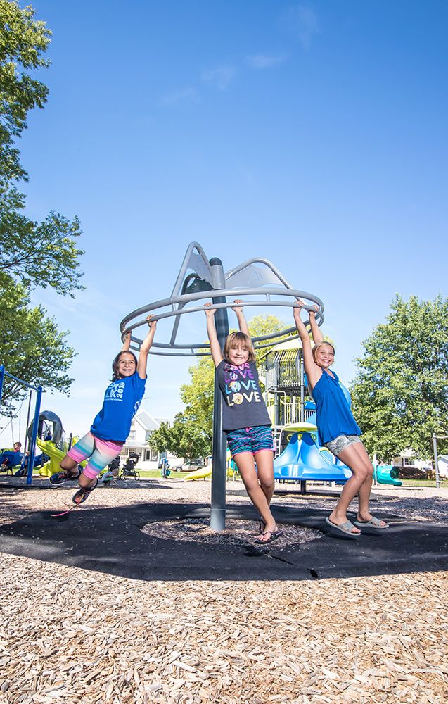 Three girls hanging on playground spinner