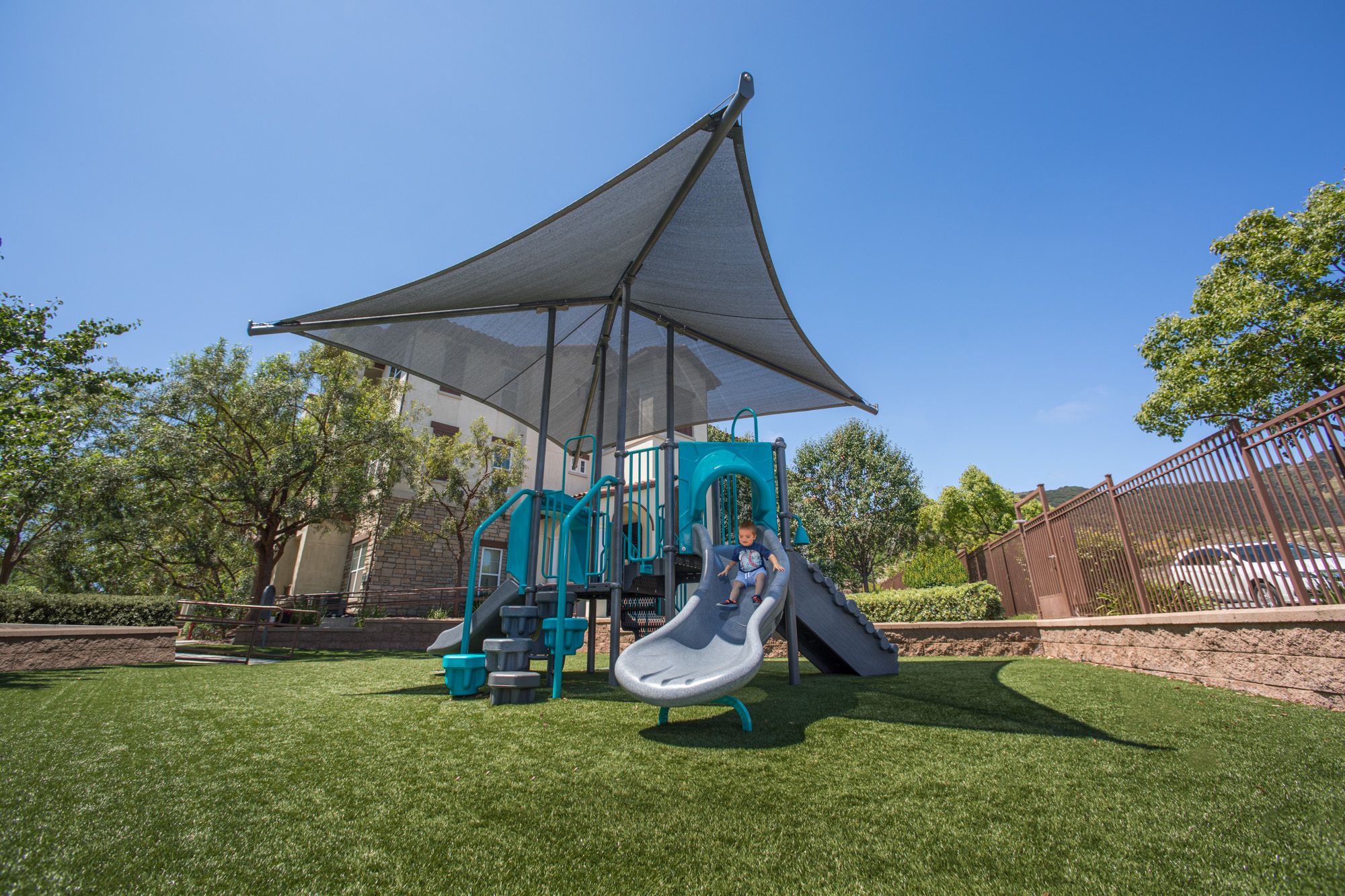 Blue and gray playground underneath gray play shade structure