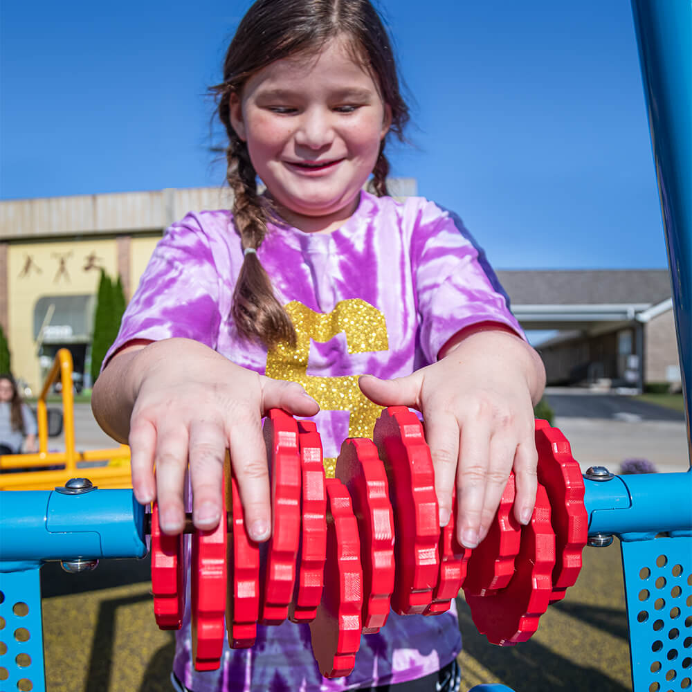 a girl wearing a tie dye shirt playing with sensory playground equipment