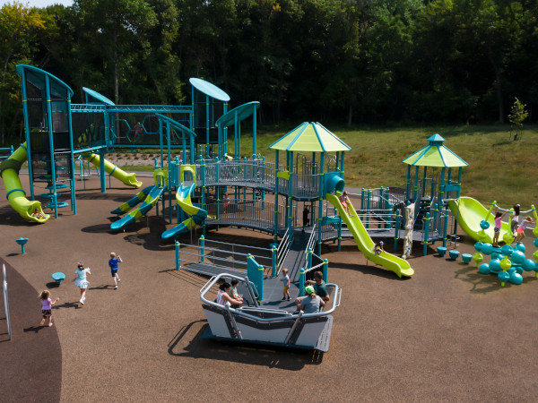 Children playing on a colorful Miracle playground that has ramps, slides, climbers and motion play